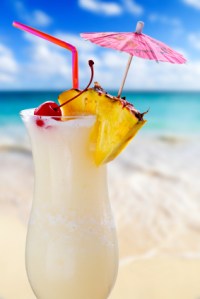 Pina colada drink in cocktail glass with tropical beach in background